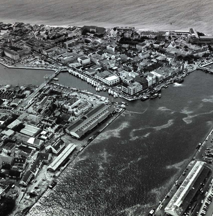 Loods van de Curaçaosche Handel Maatschappij (midden) aan de Sint Annabaai met het waaigat (linksboven) en de handelskade te Willemstad