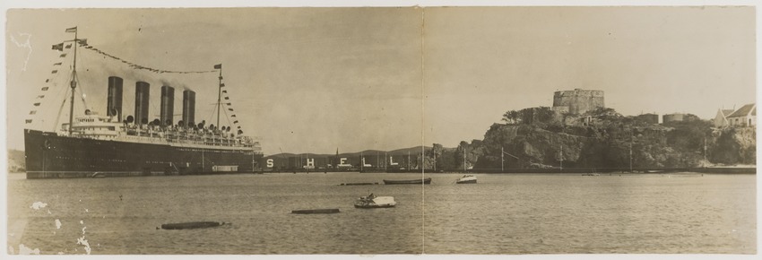 De Mauretania van de Cunard Line, het snelste Transatlantische passagiersschip, in de Caracas-baai, Curaçao, met op de achtergrond de olieopslagtanks van de Curaçaosche Petroleum Industrie Maatschappij en rechts Fort Beekenburg