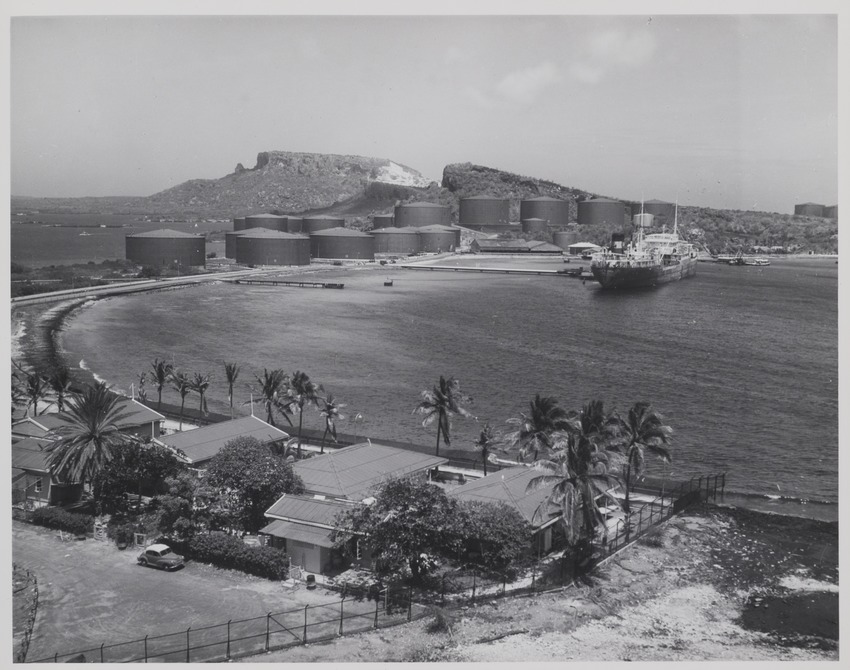Rechts het huis van Jan Carel van Essen, hoofd Fotografische Dienst van de Curaçaosche Petroleum Industrie Maatschappij, aan de Caracasbaai op Curaçao met op de achtergrond olieopslagtanks van Shell en de Tafelberg