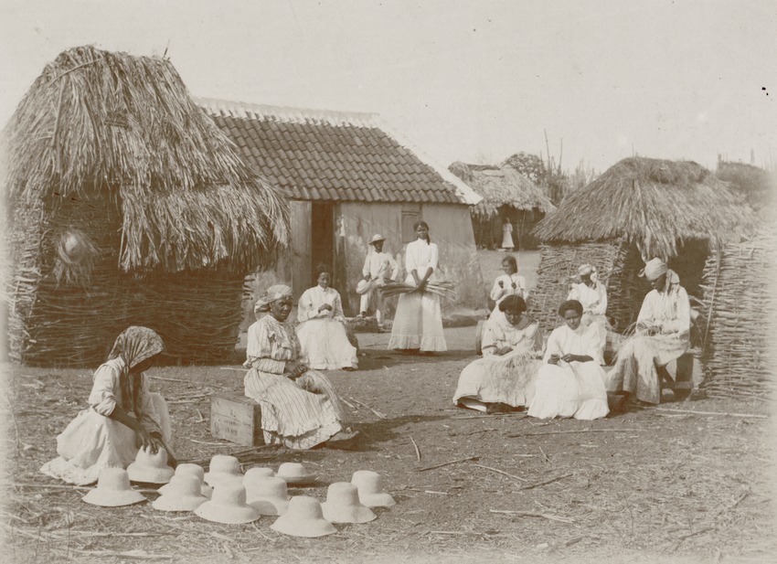 Buitenwerkende vrouwen vlechten samen strohoeden op Curaçao