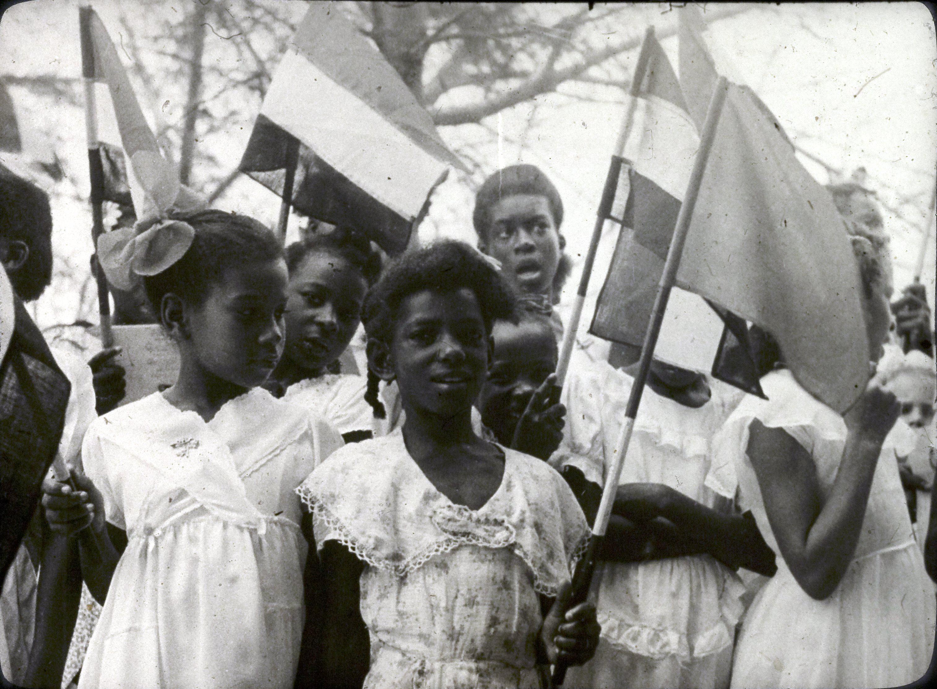 Kinderen met vlaggen, vermoedelijk ter gelegenheid van het bezoek van prins Bernhard en koningin Juliana op de Nederlandse Antillen of in Suriname